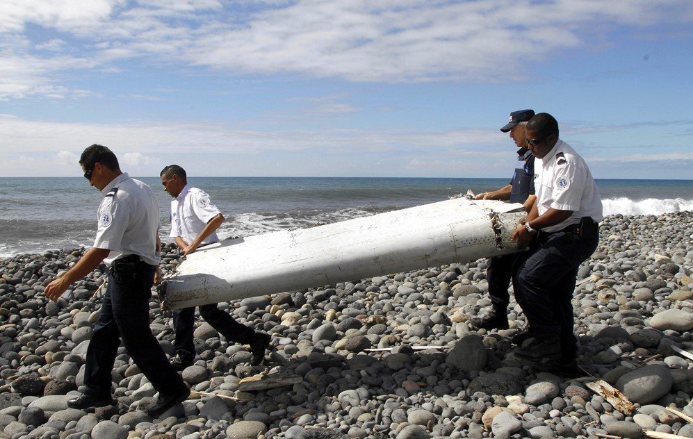 Officers carry a plane part that apparently washed ashore in on Reunion Island. French officials determined on Sept. 3, 2015 that it came from missing Malaysian Airlines Flight 370. No other debris has been found since, and the disappearance remains a mystery.